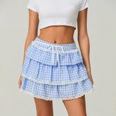 Blue checkered tiered skirt with white lace trim worn by a person on a plain background